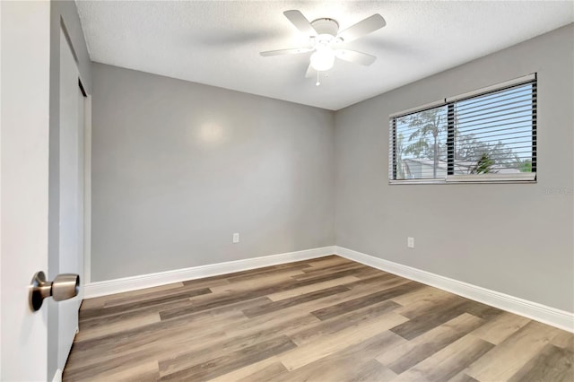 unfurnished room with wood finished floors, baseboards, a ceiling fan, and a textured ceiling