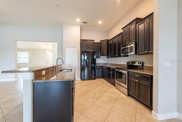12352 Crestridge Loop, New Port Richey, FL 34655 - kitchen featuring appliances with stainless steel finishes, a sink, dark stone counters, light tile patterned floors, and dark brown cabinets