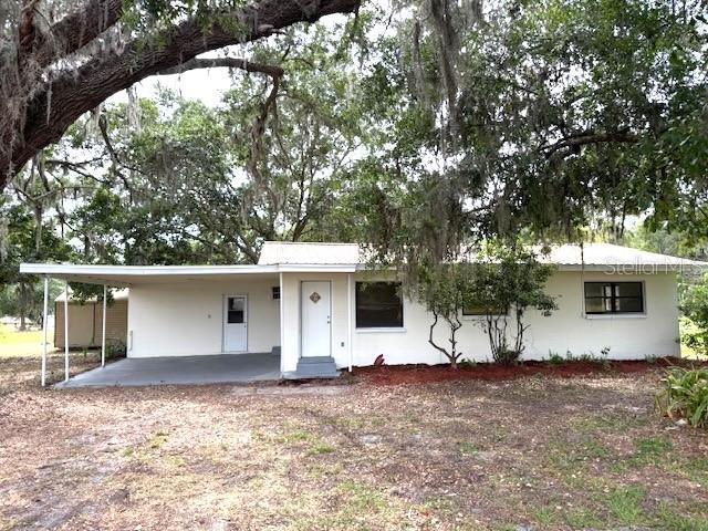 1138 Huss Rd, Wauchula, FL 33873 - view of front of house featuring a carport, stucco siding, and dirt driveway