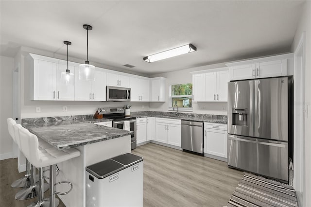 3119 W N St, Tampa, FL 33614 - kitchen featuring appliances with stainless steel finishes, a peninsula, white cabinetry, a sink, and hanging light fixtures