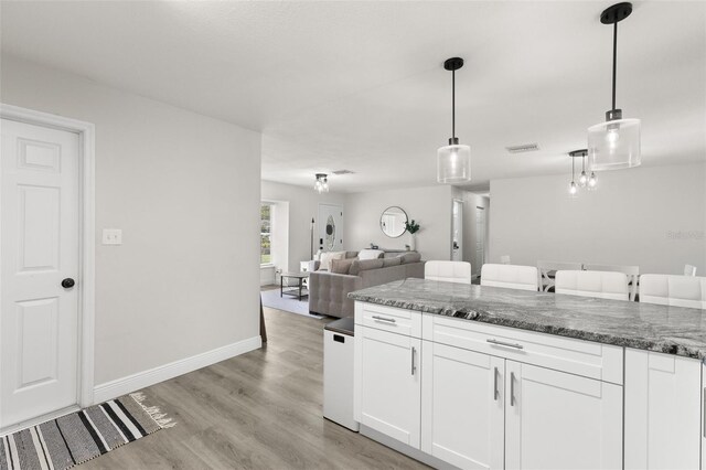 3119 W N St, Tampa, FL 33614 - kitchen with white cabinetry, light wood-type flooring, hanging light fixtures, and dark stone counters