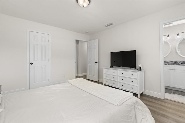 3119 W N St, Tampa, FL 33614 - bedroom featuring wood finished floors, baseboards, and ensuite bath