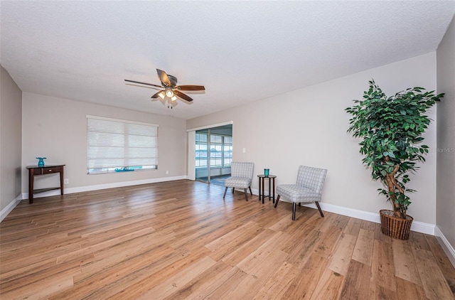 living area with ceiling fan, light wood-style floors, and baseboards