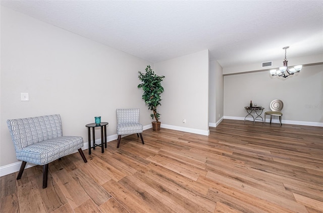 living area with light wood-type flooring, baseboards, and a chandelier