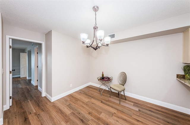 unfurnished room with wood finished floors, a chandelier, and baseboards