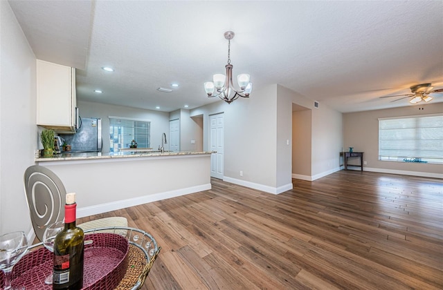 kitchen with open floor plan, a chandelier, wood-type flooring, white cabinetry, and a textured ceiling