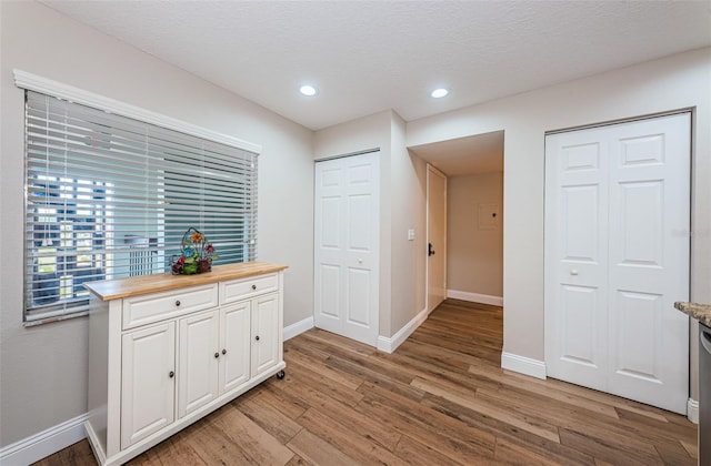 interior space featuring light wood-style flooring, baseboards, recessed lighting, and a textured ceiling