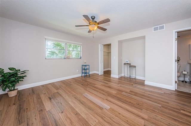 unfurnished bedroom featuring light wood finished floors, baseboards, ceiling fan, and ensuite bath
