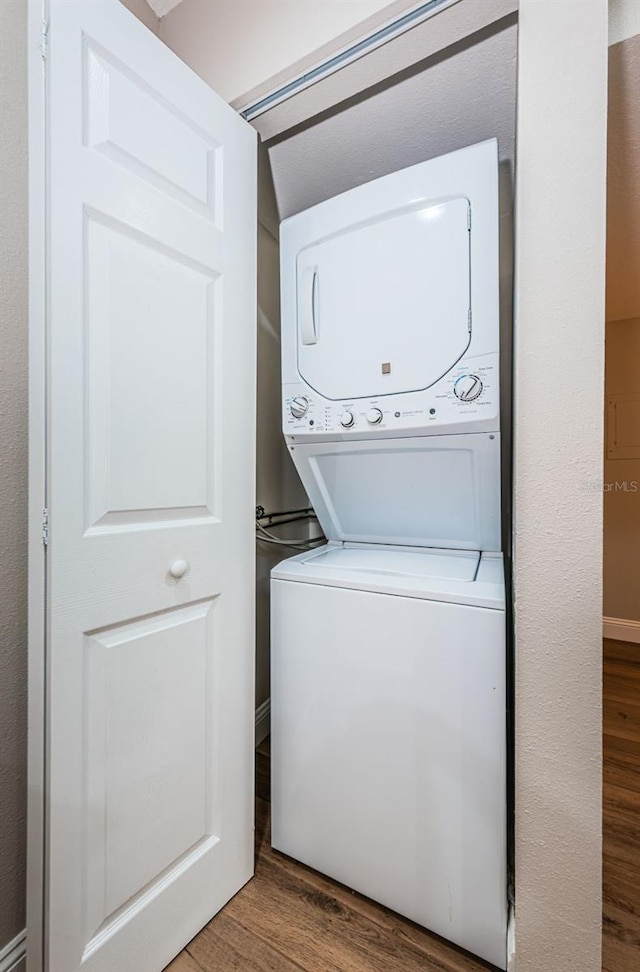 laundry room with stacked washer / drying machine and wood finished floors