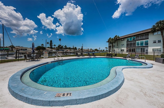 community pool with fence and a patio