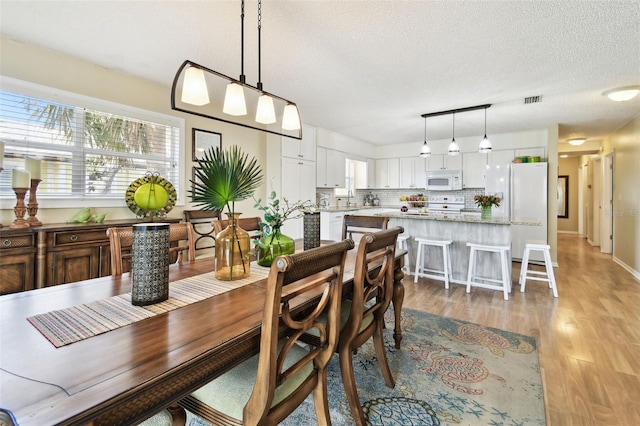 dining room with light wood-style floors and a textured ceiling