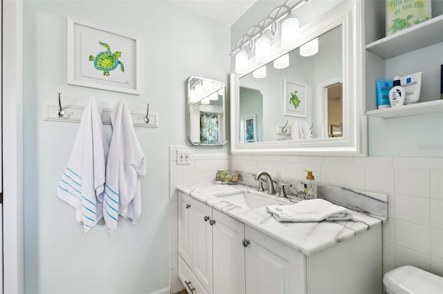 bathroom featuring tile walls, vanity, and toilet