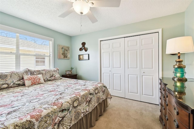 bedroom with light colored carpet, a closet, a textured ceiling, and ceiling fan