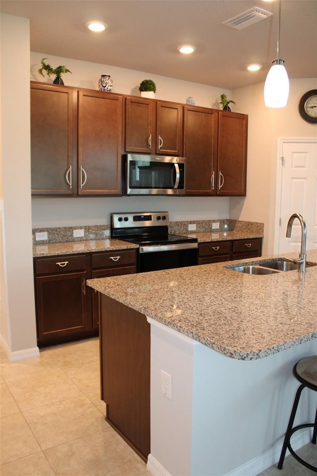 8009 Trimbelle Ter, Parrish, FL 34219 - kitchen with appliances with stainless steel finishes, a sink, a breakfast bar area, light stone counters, and recessed lighting