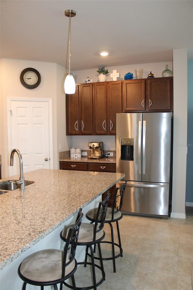 8009 Trimbelle Ter, Parrish, FL 34219 - kitchen featuring stainless steel fridge with ice dispenser, a sink, a breakfast bar area, pendant lighting, and light stone counters