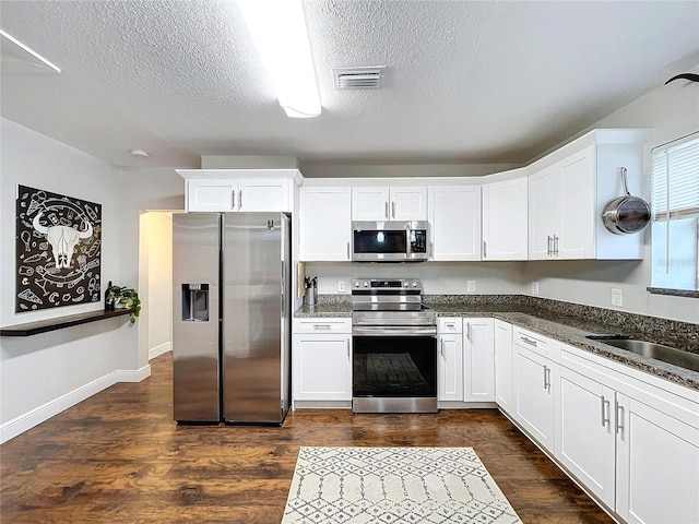 3213 E Genesee St, Tampa, FL 33610 - kitchen featuring appliances with stainless steel finishes, white cabinetry, a textured ceiling, dark wood-style floors, and a sink