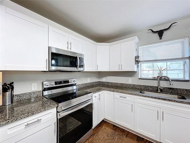 3213 E Genesee St, Tampa, FL 33610 - kitchen with stainless steel appliances, a sink, white cabinets, dark wood finished floors, and dark stone counters