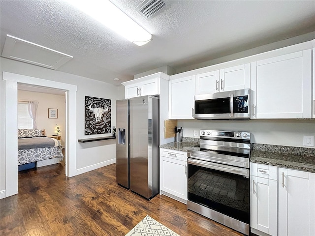 3213 E Genesee St, Tampa, FL 33610 - kitchen featuring appliances with stainless steel finishes, dark wood-type flooring, white cabinets, dark stone counters, and a textured ceiling