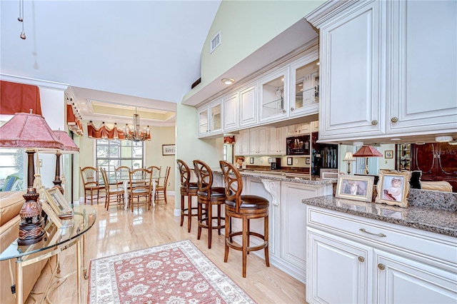 124 Barrington Dr, Brandon, FL 33511 - kitchen with a chandelier, white cabinets, light wood-type flooring, and a breakfast bar