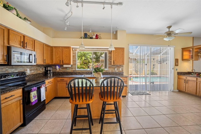 4222 Trumpworth Ct, Valrico, FL 33596 - kitchen with black range with electric cooktop, stainless steel microwave, a sink, a ceiling fan, and tasteful backsplash