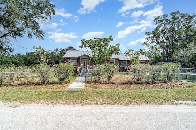 view of front of home with a fenced front yard, french doors, and metal roof