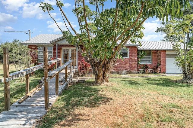 ranch-style home featuring brick siding, an attached garage, metal roof, and a front lawn