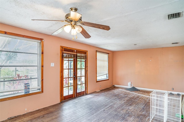 unfurnished room with a textured ceiling, wood finished floors, french doors, and a ceiling fan