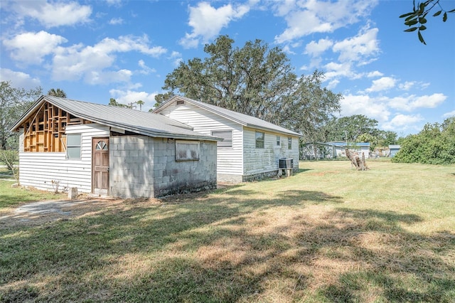 view of side of property with a yard, metal roof, and cooling unit
