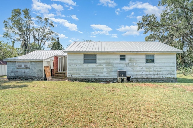 back of property with metal roof, a lawn, and central air condition unit
