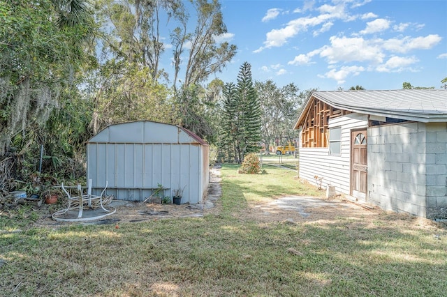 view of grassy yard with a storage unit and an outbuilding