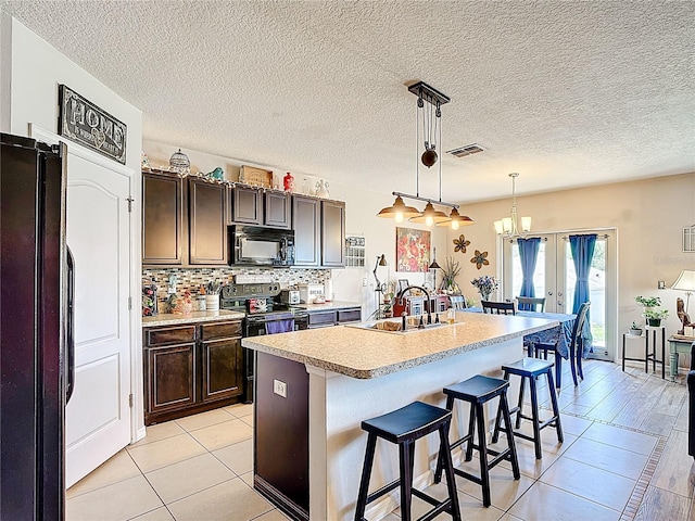 159 Lazy Willow Dr, Davenport, FL 33897 - kitchen with black appliances, a kitchen breakfast bar, light countertops, light tile patterned floors, and a textured ceiling