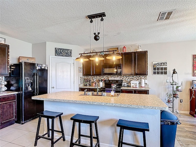159 Lazy Willow Dr, Davenport, FL 33897 - kitchen with black appliances, light countertops, a breakfast bar area, dark brown cabinets, and a sink