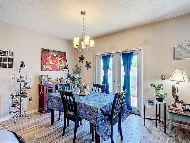 159 Lazy Willow Dr, Davenport, FL 33897 - dining space with light wood-style flooring, french doors, a chandelier, baseboards, and a textured ceiling