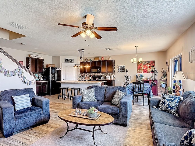 159 Lazy Willow Dr, Davenport, FL 33897 - living area featuring a textured ceiling, light wood finished floors, a chandelier, and a ceiling fan