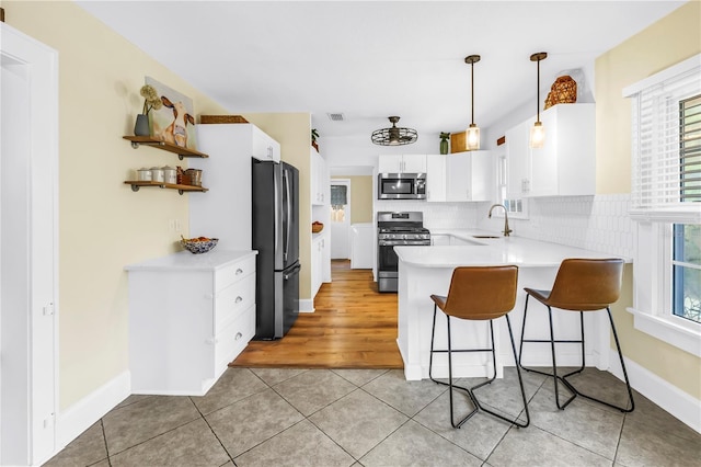 kitchen featuring appliances with stainless steel finishes, a peninsula, open shelves, and white cabinets