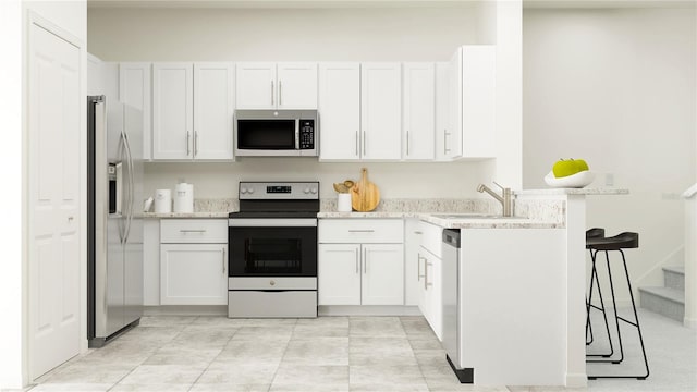 kitchen featuring stainless steel appliances, a sink, a breakfast bar area, and white cabinetry