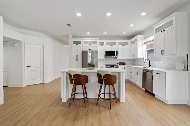5628 Terrain De Golf Dr, Lutz, FL 33558 - kitchen with appliances with stainless steel finishes, a kitchen island, tasteful backsplash, light wood finished floors, and light countertops