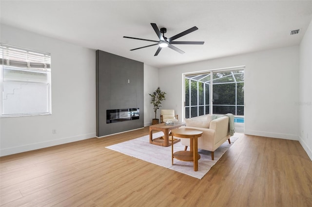 5628 Terrain De Golf Dr, Lutz, FL 33558 - living area with light wood finished floors, a ceiling fan, baseboards, and a large fireplace