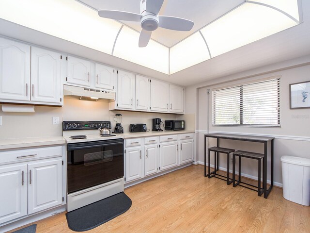 640 Bayway Blvd Unit 302, Clearwater Beach, FL 33767 - kitchen with range with electric cooktop, under cabinet range hood, black microwave, light countertops, and white cabinets