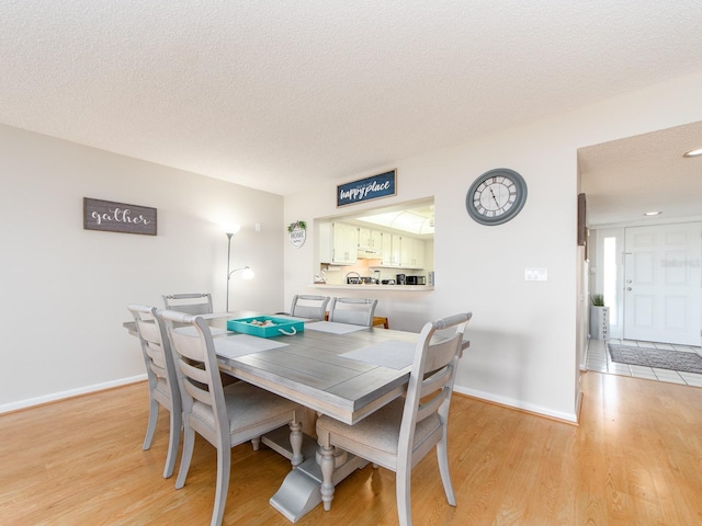 640 Bayway Blvd Unit 302, Clearwater Beach, FL 33767 - dining area with a textured ceiling, light wood-style floors, and baseboards