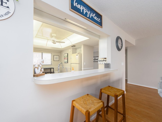 640 Bayway Blvd Unit 302, Clearwater Beach, FL 33767 - kitchen featuring freestanding refrigerator, wood finished floors, a breakfast bar area, a ceiling fan, and baseboards