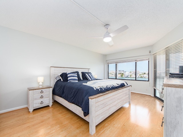 640 Bayway Blvd Unit 302, Clearwater Beach, FL 33767 - bedroom featuring light wood-type flooring, baseboards, ceiling fan, and a textured ceiling