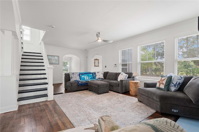 living area with dark wood finished floors, a ceiling fan, stairs, and arched walkways