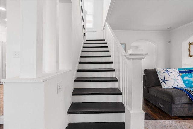 stairway featuring crown molding, arched walkways, and wood finished floors