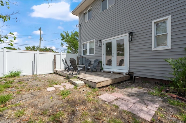 rear view of house featuring fence, a wooden deck, and french doors