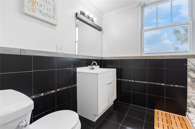 bathroom with tile walls, toilet, ornamental molding, vanity, and tile patterned floors