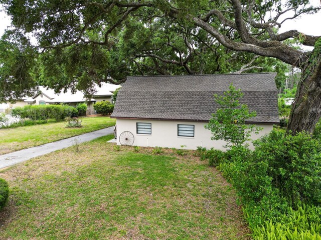 7216 N Mobley Rd, Odessa, FL 33556 - view of side of home with stucco siding, a shingled roof, and a yard