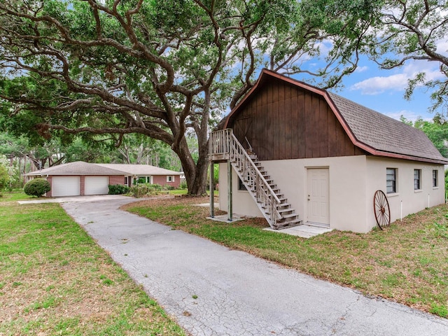 7216 N Mobley Rd, Odessa, FL 33556 - view of front facade with an outdoor structure, stairs, a front yard, a gambrel roof, and roof with shingles