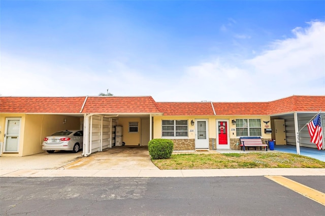 multi unit property featuring mansard roof, stone siding, and a shingled roof