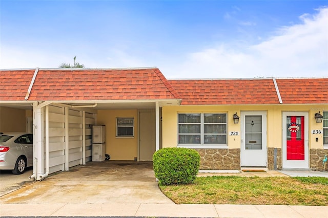 townhome / multi-family property with an attached carport, roof with shingles, and mansard roof